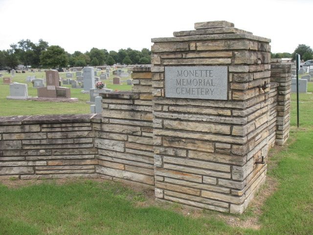 Monette Memorial Cemetery stone entrance gate with headstones and trees in the background